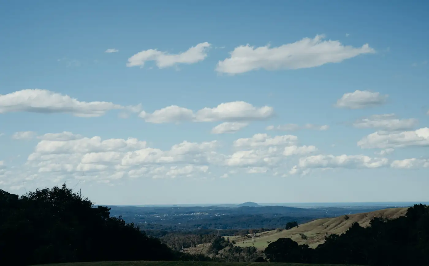 Green hinterland hills under a blue sky with the coast in the distance
